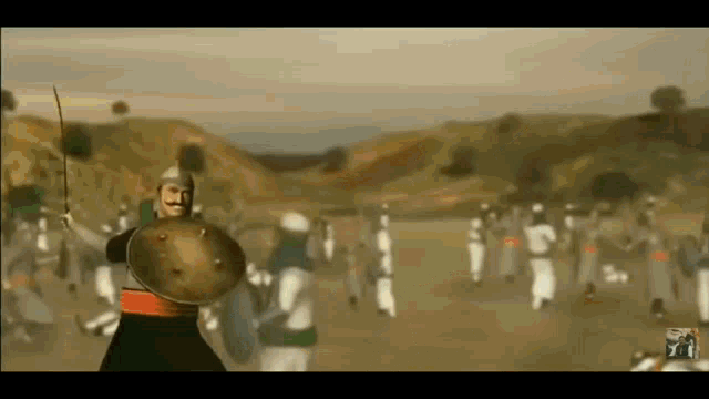 a man holding a sword and shield stands in front of a crowd of soldiers