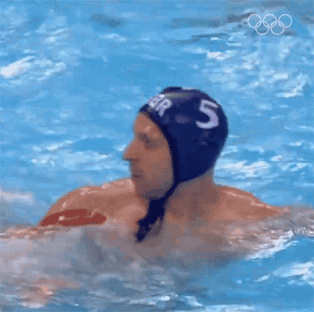 a man in a swimming pool with the number 5 on his hat