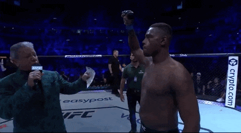 a man stands in a boxing ring with his arm raised