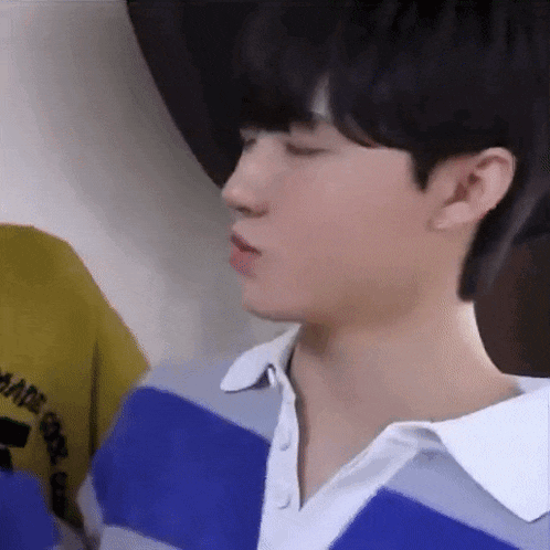 a close up of a young man wearing a blue and white striped shirt and a yellow shirt .