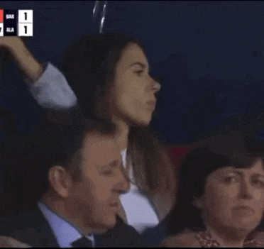 a man and a woman are sitting in a stadium watching a soccer game .