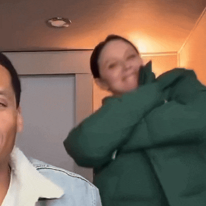 a man and a woman are standing next to each other . the woman is wearing a green jacket .