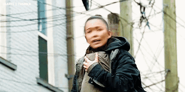 a woman in a black jacket is holding a child in her arms .