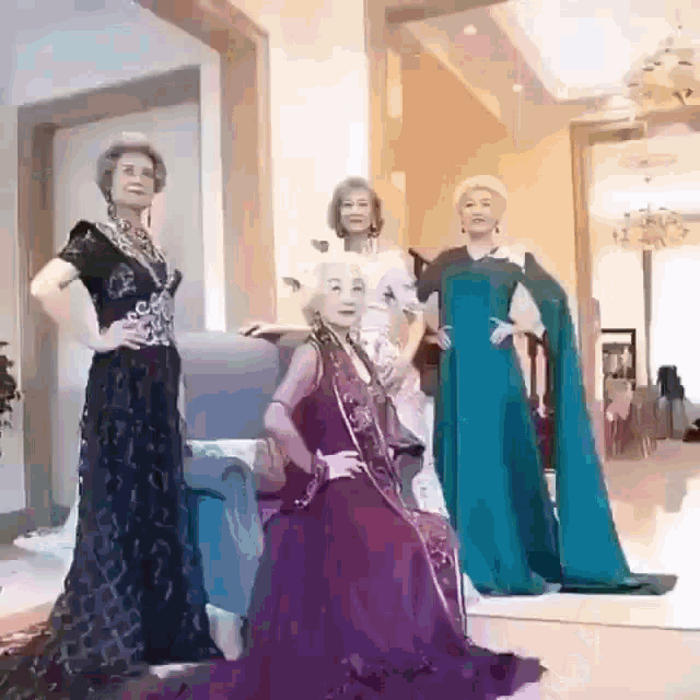 a group of older women are posing for a picture while wearing fancy dresses .