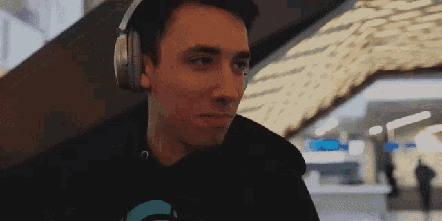 a man wearing headphones and a black hoodie with a blue circle on it