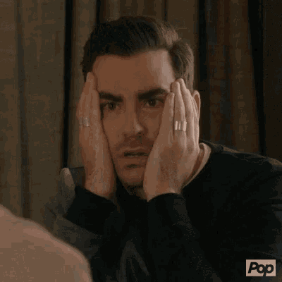 a man is covering his face with his hands while wearing a ring .
