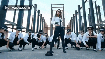 a woman is dancing in front of a group of dancers wearing hats .