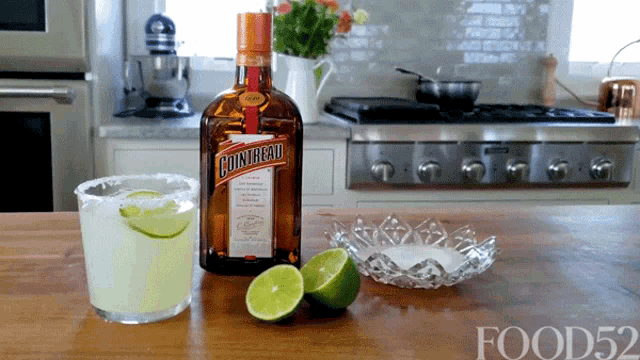 a bottle of cointreau sits on a counter next to a margarita