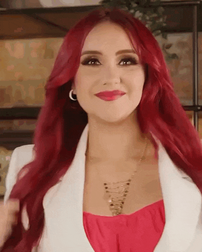a woman with red hair is wearing a white jacket and a pink top .