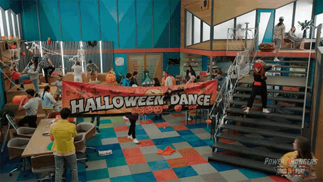 a group of people are gathered in a room holding a halloween dance banner