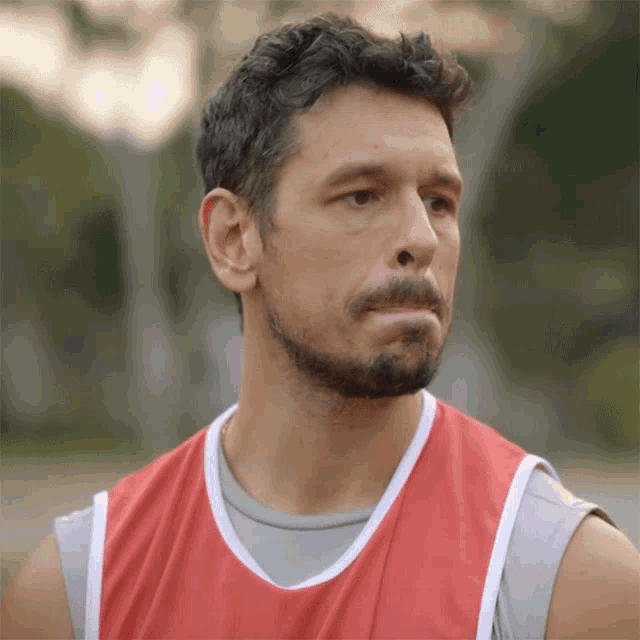 a man with a beard wearing a red tank top