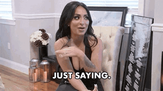 a woman is sitting in a chair in a living room and saying `` just saying . ''