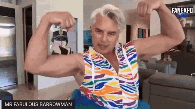 a man is flexing his muscles while wearing a colorful shirt and a tutu .