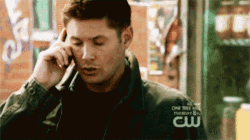 a man is talking on a cell phone while wearing a jacket with the word cw on it .
