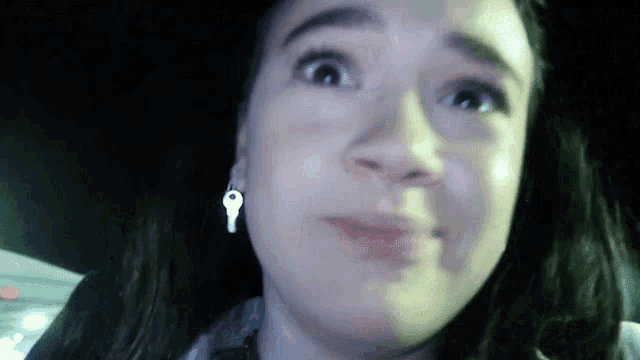 a close up of a woman 's face with a key earring