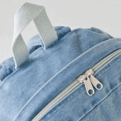 a close up of a blue denim backpack with a white handle and zipper