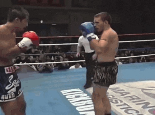 two men are boxing in a ring with a sign that says kickboxing on it