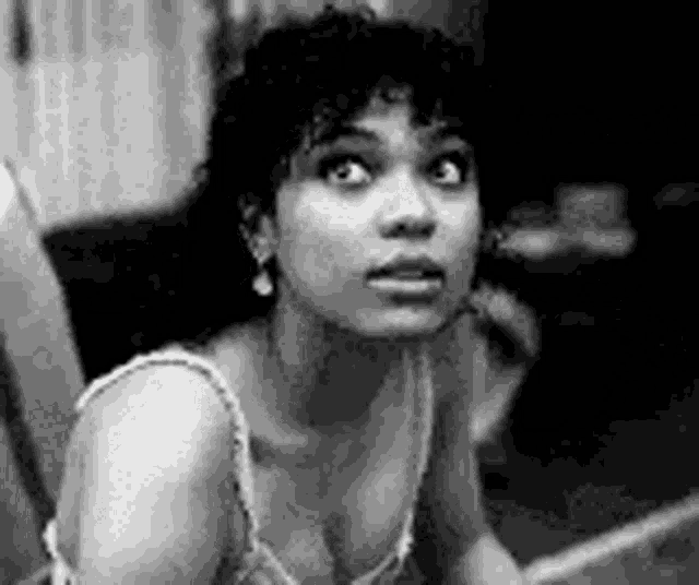 a black and white photo of a woman with curly hair looking up .
