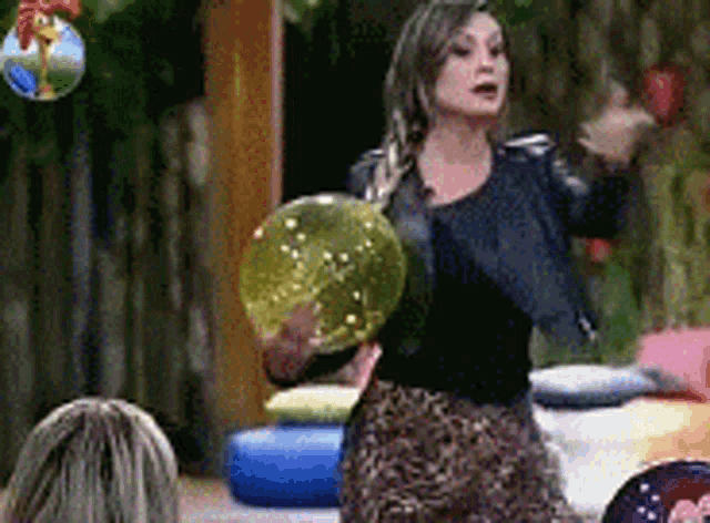 a woman is holding a green ball in her hand while standing in front of a group of people .