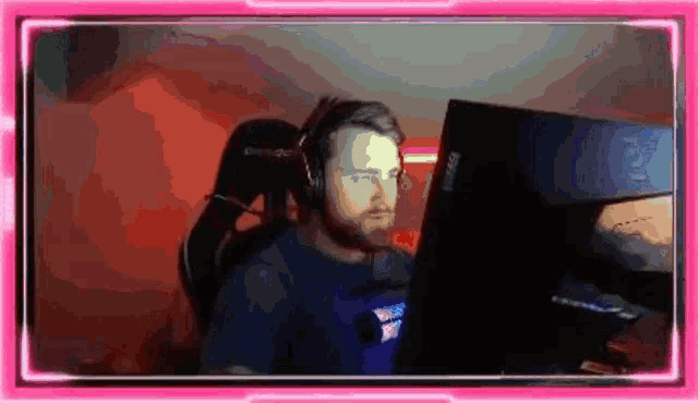 a man is sitting in front of a computer screen wearing headphones and a headset .