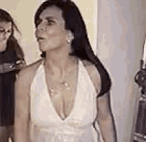 a woman in a white dress with a plunging neckline is standing next to a woman in a black dress .