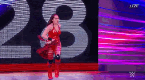 a woman in a red dress and red boots is walking down a stage .