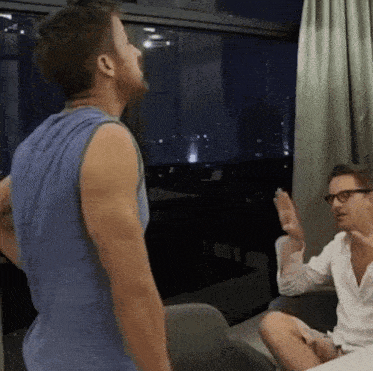 a man in a blue tank top is talking to another man