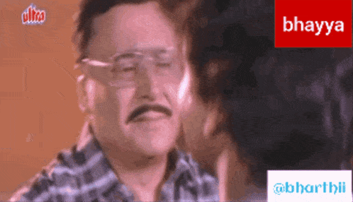 a man with glasses and a mustache is being kissed by a woman behind a sign that says bhagya