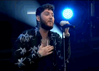 a man is singing into a microphone in front of a blue light .