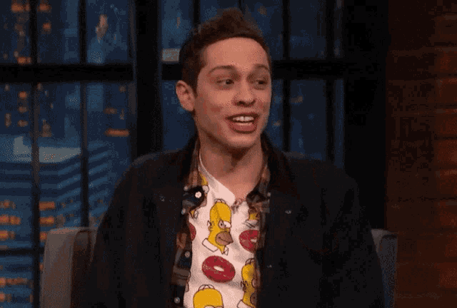 a man wearing a shirt that has homer simpson on it gives a thumbs up