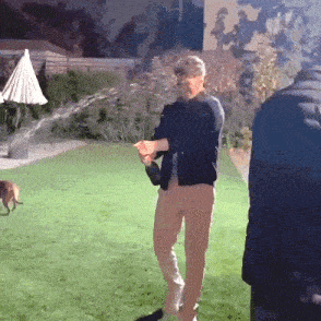a man is standing on a lush green lawn with a bottle of champagne in his hand