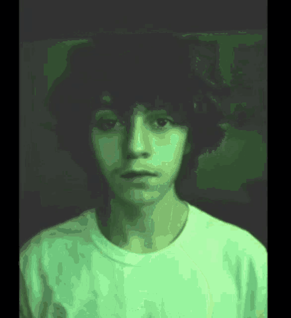 the boy is wearing a white shirt and has a green background .