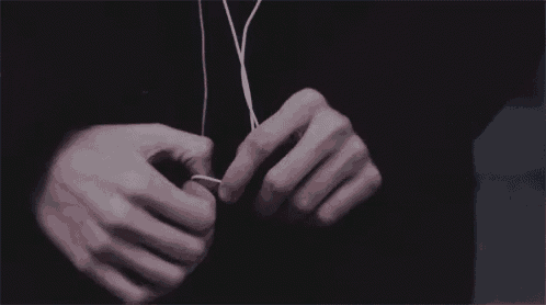a close up of a person 's hands tying a pair of earphones .