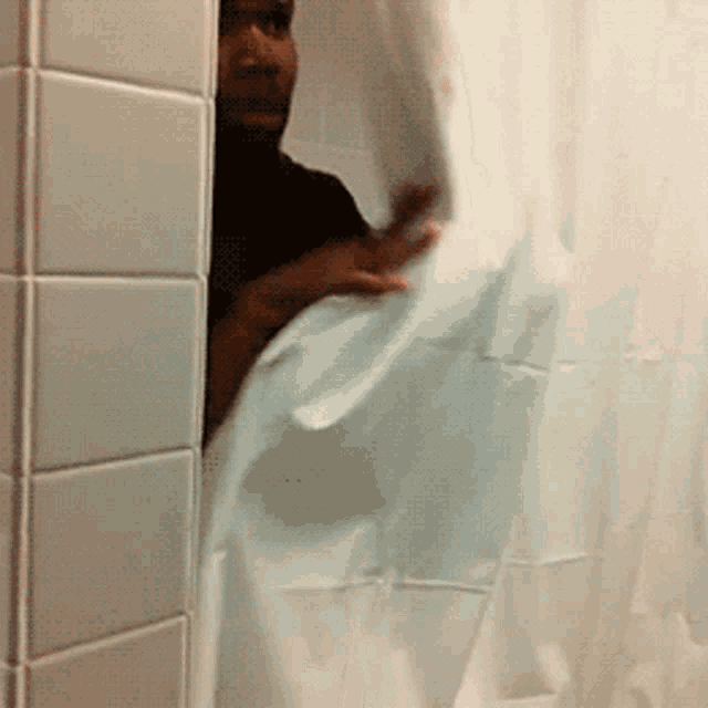 a man peeking out of a shower curtain in a bathroom