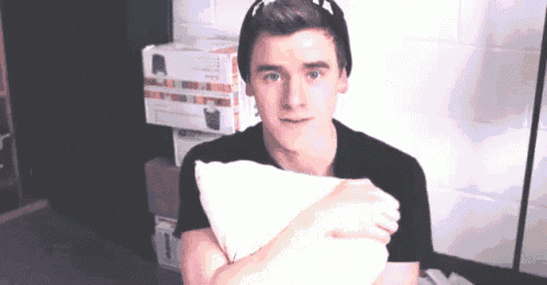 a young man is holding a white pillow in his hands