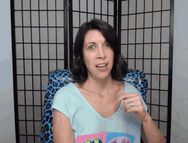 a woman wearing a batman shirt is sitting in a chair