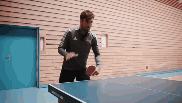 a man is playing ping pong on a table that has the word tenergy on it