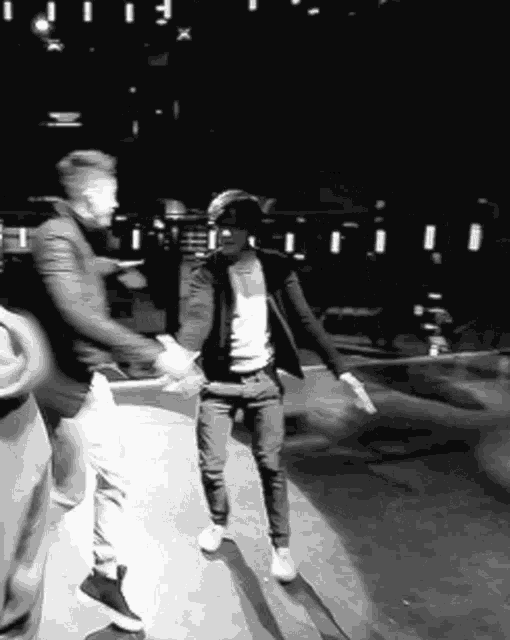 a black and white photo of two men shaking hands in a dark room