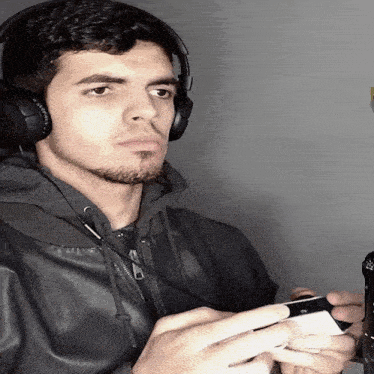 a man wearing headphones and a leather jacket holds a game controller