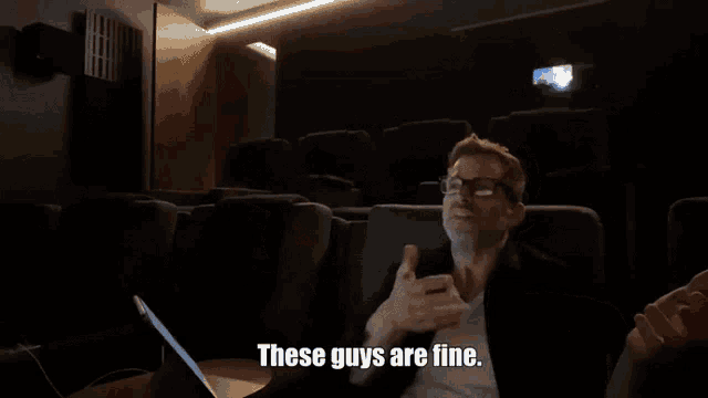 a man sitting in an auditorium with the words these guys are fine