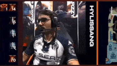 a man wearing headphones and a shirt that says sea is sitting in front of a screen .