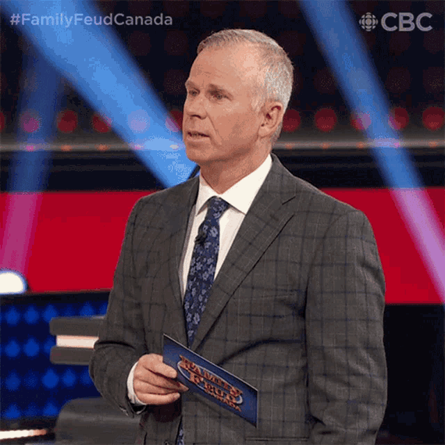 a man in a suit and tie is holding a card that says family feud canada on it