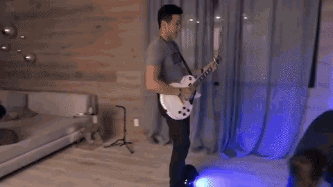 a man in a nyc shirt is playing an electric guitar in a living room
