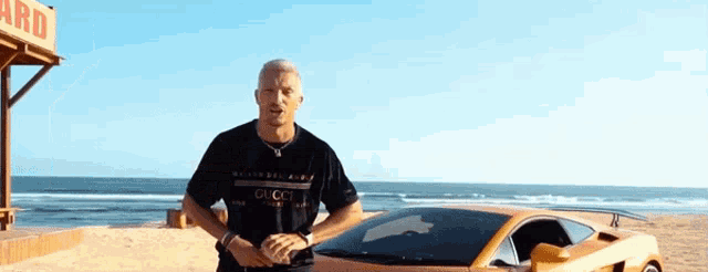 a man wearing a gucci shirt stands next to a car