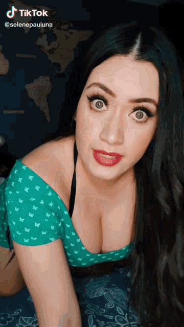 a woman in a green top is kneeling down and looking at the camera with a tiktok logo above her