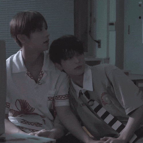 two young men are sitting next to each other with one wearing a shirt with the letter r on the sleeve