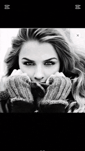 a black and white photo of a woman wearing gloves and a scarf