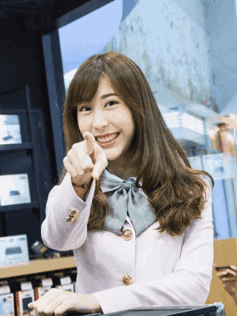 a woman in a pink jacket is smiling and pointing