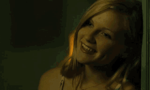 a woman leaning against a wall and smiling