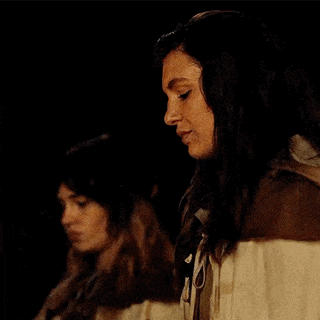 a woman with long dark hair is drinking from a glass in a dark room